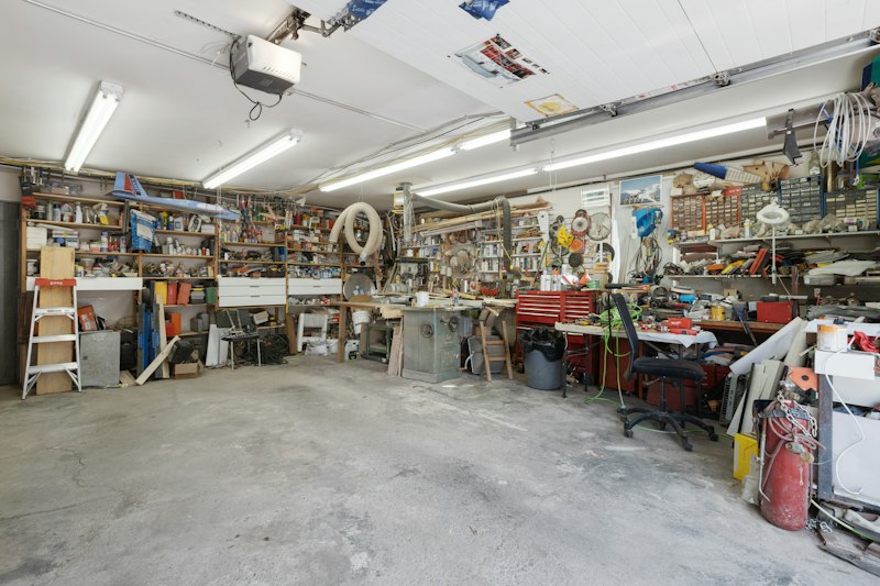 A residential garage packed with tools, shelves, and stored household items